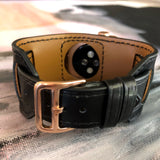 Black Apple Watch Leather Cuff by Juxli Home.  Handmade, stylish leather strap with rose gold hardware on a 40mm Apple watch on a canvas with a black and gray painting.