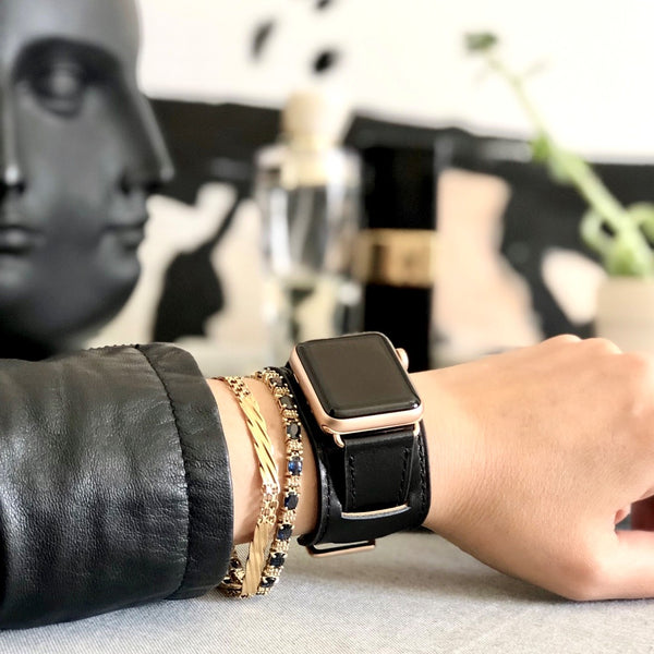 Black Apple Watch Leather Cuff by Juxli Home. Handmade, stylish leather strap with rose gold hardware on a 40mm Apple watch on a canvas with a black and gray painting.