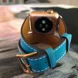Cyan Blue Double Wrap Apple Watch Leather Band by Juxli Home.  Handmade, stylish leather strap with rose gold hardware on a 40mm Apple watch on a canvas with a black and gray painting.