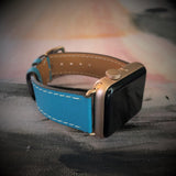 Cyan Blue Apple Watch Band by Juxli Home.  Handmade, stylish leather strap with rose gold hardware on a 40mm Apple watch on a canvas with a black and gray painting.
