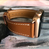Cognac Brown Apple Watch Leather Band by Juxli Home.  Handmade, stylish leather strap with rose gold hardware on a 40mm Apple watch on a canvas with a black and gray painting.