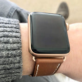 Cognac Brown Apple Watch Leather Band by Juxli Home.  Handmade, stylish leather strap with rose gold hardware on a 40mm Apple watch on a canvas with a black and gray painting.