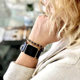 Space Blue Apple Watch Double Buckle Leather Cuff by Juxli Home.  Handmade, stylish leather strap with rose gold hardware on a 40mm Apple watch on a canvas with a black and gray painting.