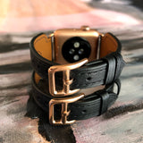 Black Double Buckle Apple Watch Leather Cuff by Juxli Home.  Handmade, stylish leather strap with rose gold hardware on a 40mm Apple watch on a canvas with a black and gray painting.