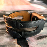 Black Double Buckle Apple Watch Leather Cuff by Juxli Home.  Handmade, stylish leather strap with rose gold hardware on a 40mm Apple watch on a canvas with a black and gray painting.