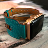 Sea Green Apple Watch Double Buckle Leather Cuff by Juxli Home.  Handmade, stylish leather strap with rose gold hardware on a 40mm Apple watch on a canvas with a black and gray painting.