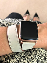 Women’s Ivory Double Wrap Apple Watch Leather Band by Juxli Home.  Handmade, stylish leather strap with rose gold hardware on a 40mm Apple watch on a canvas with a black and gray painting.