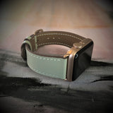 Sage Gray Apple Watch Band by Juxli Home.  Handmade, stylish leather strap with rose gold hardware on a 40mm Apple watch on a canvas with a black and gray painting.