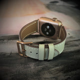 Sage Gray Apple Watch Band by Juxli Home.  Handmade, stylish leather strap with rose gold hardware on a 40mm Apple watch on a canvas with a black and gray painting.