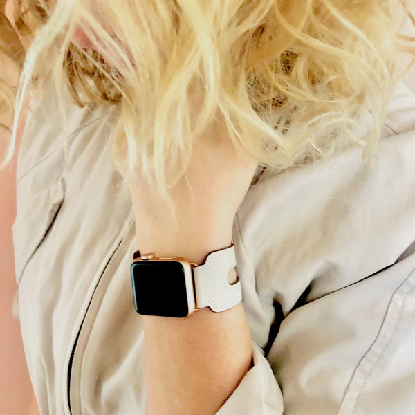 Ivory Apple Watch Double Buckle Cuff by Juxli Home. Handmade, stylish leather strap with rose gold hardware on a 40mm Apple watch on a canvas with a black and gray painting.