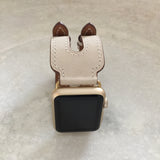 Ivory Apple Watch Double Buckle Cuff by Juxli Home.  Handmade, stylish leather strap with rose gold hardware on a 40mm Apple watch on a canvas with a black and gray painting.
