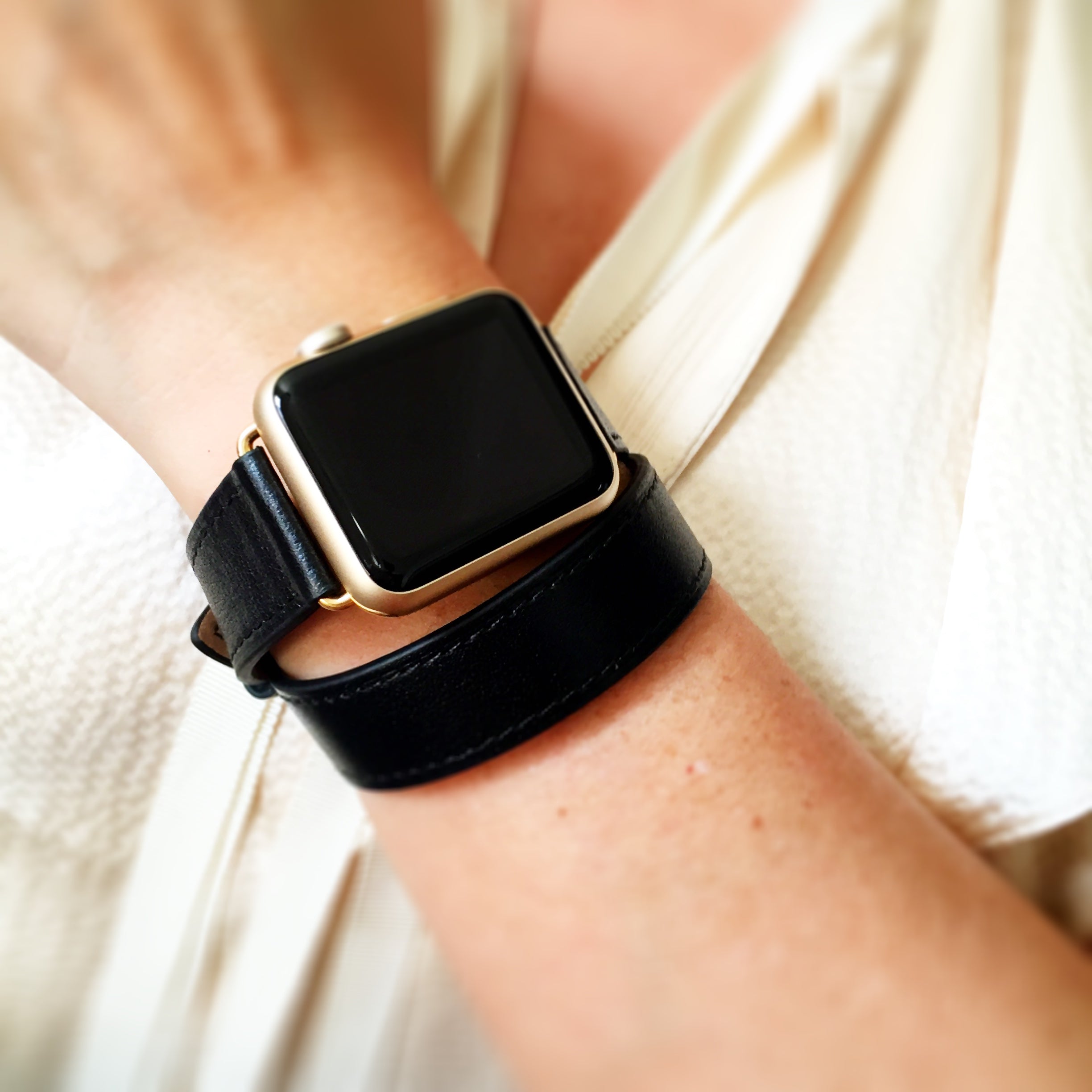 Jet Black Double Wrap Apple Watch Leather Band by Juxli Home.  Handmade, stylish leather strap with rose gold hardware on a 40mm Apple watch on a canvas with a black and gray painting.