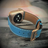 Cyan Blue Apple Watch Band by Juxli Home.  Handmade, stylish leather strap with rose gold hardware on a 40mm Apple watch on a canvas with a black and gray painting.