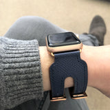 Space Blue Apple Watch Double Buckle Leather Cuff by Juxli Home.  Handmade, stylish leather strap with rose gold hardware on a 40mm Apple watch on a canvas with a black and gray painting.