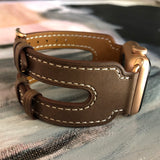 Chocolate Brown Double Buckle Apple Watch Leather Cuff by Juxli Home.  Handmade, stylish leather strap with rose gold hardware on a 40mm Apple watch on a canvas with a black and gray painting.