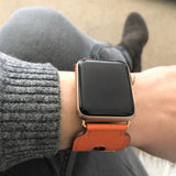 Summer Orange Double Buckle Apple Watch Leather Cuff by Juxli Home.  Handmade, stylish leather strap with rose gold hardware on a 40mm Apple watch on a canvas with a black and gray painting.