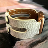 White Apple Watch Double Buckle Leather Cuff by Juxli Home.  Handmade, stylish leather strap with rose gold hardware on a 40mm Apple watch on a canvas with a black and gray painting.
